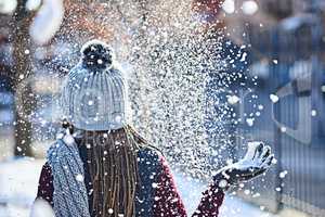 She turns snow into glitter. Rearview shot of a young woman throwing snow on a wintery day outdoors.