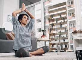 We earn our peace. Shot of an attractive young woman meditating on her bedroom floor at home.