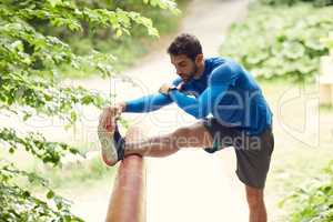 The more you stretch, the less you stress. Shot of a sporty man starting his exercise routine with stretching exercises.