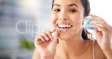 Dental hygiene is a priority. Shot of a young woman flossing her teeth at home.
