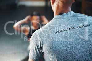 A trainer can make your exercise program a lot more effective. Closeup shot of a personal trainer assisting a client in a gym.