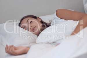 Sleep needs no explanation and is its own excuse. Shot of a young female sleeping in bed at home.