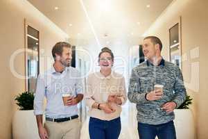 We take brakes now and then too. Portrait of a group of young businesspeople walking together down a passage while drinking coffee.