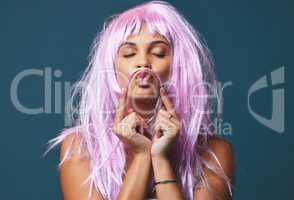 Obey their rules, miss the fun. Studio shot of a beautiful young woman posing with a playful pink wig against a blue background.