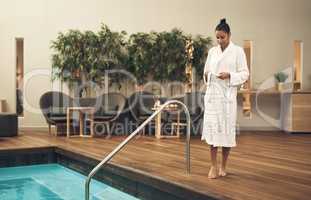 Im going for a dip. Shot of a woman taking off her robe before getting into swimming pool at a spa resort.
