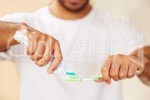 The right toothpaste makes all the difference. Cropped shot of a man putting toothpaste on his toothbrush.