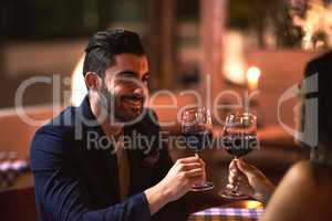 To a fine night out. Shot of a cheerful young couple having a celebratory toast with wine glasses while looking into each others eyes over dinner outside at night.