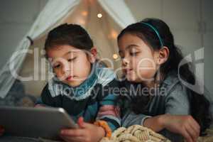 A sister is a forever friend. Shot of two sisters using a digital tablet at home.