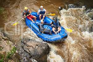 Through the rapids. High angle shot of a group of young friends white water rafting.