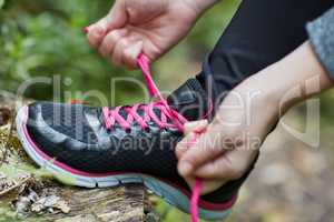Laced up and ready to go. Shot of an unidentifiable young woman tying her shoelaces while hiking in the forest.