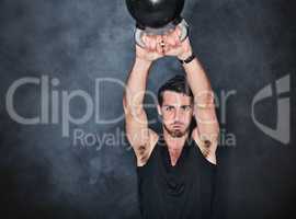 Strong is a doing word. Studio shot of a young man working out with a kettle bell against a gray background.