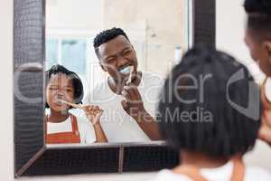 Make sure you get every tooth. Shot of a young father bonding with his daughter while they brush their teeth in the bathroom at home.