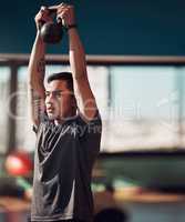 One more rep should do it. Shot of a young man working out using a kettlebell in the gym.