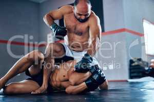 Its all about tactics. Shot of a male fighter about to punch another male fighter while in combat on the floor at the gym.