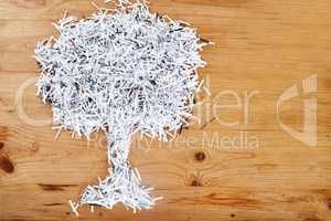 Save the environment. Recycle. Studio shot of shredded paper arranged in the shape of a tree on a wooden table.