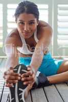 Getting into the workout groove. Shot of a sporty young woman stretching before her workout.