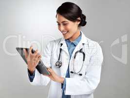 Get connected for medical advice on demand. Studio shot of a young doctor using a digital tablet against a grey background.