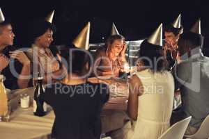 We hope all her wishes come true. Shot of a beautiful young woman blowing the candles on her birthday cake at a evening gathering with friends.