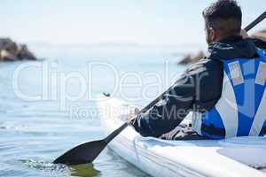 Open water is a highway to adventure. Rearview shot of a young man kayaking at a lake.