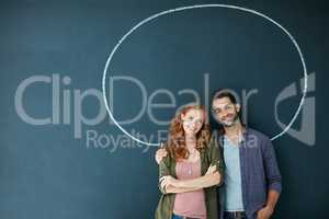 Encircled by their love. Portrait of a young couple standing in front of a blackboard with a circle drawn around them.