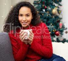 This is the Christmas spirit, as in spirits, booze. Shot of a young woman drinking coffee on the couch at home.
