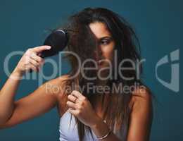 Its not just a hairstyle, its a state of mind. Studio shot of a beautiful young woman holding a brush to her hair posing against a blue background.