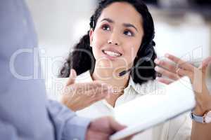 Sharing her input to find the best solution. Shot of a young call centre agent talking to a colleague in an office.