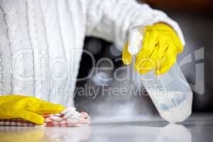 Always use a strong disinfectant. Shot of a woman spraying her kitchen counter to clean it.