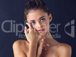 Her gaze makes your heart beat non stop. Studio shot of an attractive young woman posing and gently touching her face and neck.