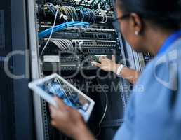 Sorting out network issues. Rearview shot of an unrecognizable female programmer working on a tablet in a server room.
