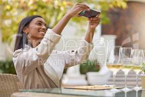 This has to go on my blog. Shot of an attractive young woman sitting alone during a wine tasting and using her cellphone to take a picture.