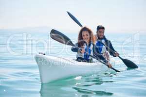 We row together, we grow together. Portrait of a young couple kayaking together at a lake.