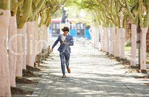 I sweat money and the bank is my shower. Full body shot of a young businessman rushing down the street and checking his watch against an urban background.