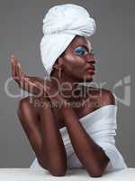 Sophisticated in a headscarf. Studio shot of an attractive young woman posing in traditional African attire against a grey background.