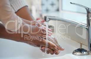 Prevent disease and wash your hands please. Shot of an unrecognisable man helping his child wash their hands in the sink at home.