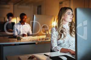 Theres no questioning her dedication. Shot of a young businesswoman working late on a computer in an office.