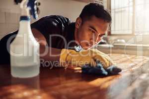 As squeaky clean as a kitchen should be. Shot of a young man disinfecting a kitchen counter at home.