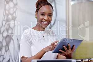 Bring me your concerns. Portrait of a young woman using a digital tablet in a modern office.