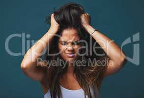 A decision made in anger is a wrong ONE. Studio shot of a beautiful young woman with her hands in her hair posing against a blue background.