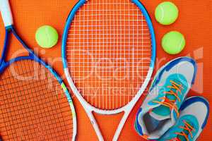 Now I just need an opponent. High angle shot of tennis essentials placed on top of an orange background inside of a studio.