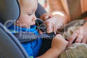 Ensuring hes safely fastened in the seat. Cropped shot of a mother fastening her baby boy safely in a car seat.