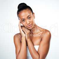 It takes a lot be flawless. Studio shot of an attractive young woman posing and gently touching her face while standing against a white background.