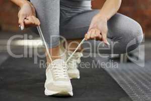 Tightening and fastening before she starts. Closeup shot of an unrecognisable woman tying her shoelaces while exercising in a gym.