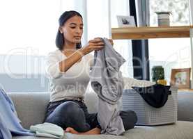Time to put these clothes away. Shot of a young woman folding laundry at home.