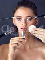 Its hard work to maintain good looks. Studio shot of an attractive young woman posing while cosmetics are applied on her face.