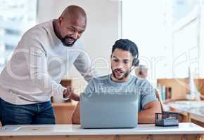 Its quite a simple process. Shot of a businessman teaching his staff member in a call center.