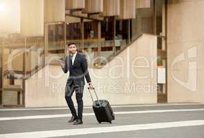They better have flight details. Shot of a businessman walking around town with his luggage using his smartphone.
