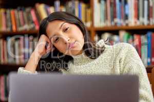 Dont let fear of failure put you off. Shot of a hispanic female using a laptop and being stressed in a library.