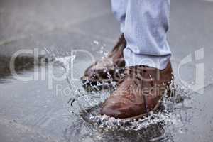 Slippery when wet. Shot of a unrecognizable man walking in a puddle of water outside.