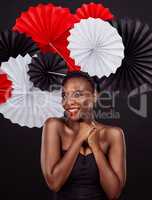 Nothing says Japan like a beautifully folded fan. Studio shot of a beautiful young woman posing with a origami fans against a black background.